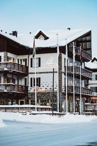 un hôtel dans la neige avec des drapeaux devant lui dans l'établissement Levin Alppitalot Alpine Chalets Deluxe, à Levi