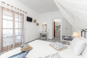 a white bedroom with a bed and a window at Zanneta Apartments & Suites in Mikri Vigla