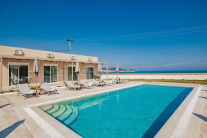 een zwembad met stoelen en een gebouw en de oceaan bij Cinque Terre Kamelia in Zakynthos