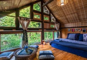 La Maison House & Bungalow في سابا: غرفة نوم في منزل شجرة مع سرير ونوافذ