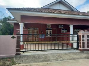 una casa con una puerta roja delante de ella en MUAZDIANA HOMESTAY di KUALA NERUS, GONG BADAK en Kampong Tanjong Gelam