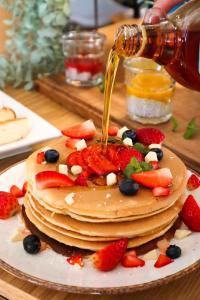 a stack of pancakes with strawberries and fruit on a plate at Hotel Faros Gdansk Airport in Gdańsk-Rębiechowo