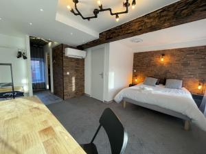 a bedroom with a bed and a brick wall at Villa Kiara Hébergements in Cusset
