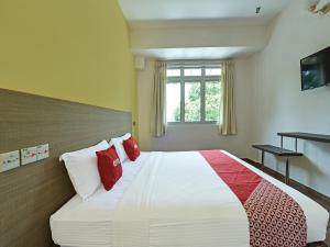 1 dormitorio con 1 cama blanca grande con almohadas rojas en Super OYO 44036 Hotel De Perdana Hill, en Batu Pahat