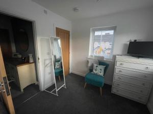 a bedroom with a mirror and a chair and a dresser at Abbey’s Inn in Cheadle