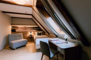 Hotel Einbecker Hof في آينبك: غرفة نوم في العلية مع سرير ومكتب وكرسي
