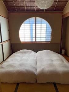1 cama blanca grande en una habitación con ventana en unsui 武雄蓬莱町 雲水, en Takeo