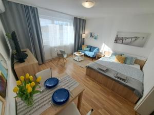 um pequeno quarto com uma cama e uma mesa com flores em Adam apartmán em Košice