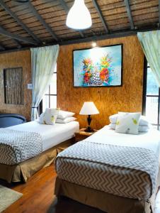 a bedroom with two beds and a painting on the wall at Resort D Rumah Bonda River View Kuala Kangsar in Kampong Senawar