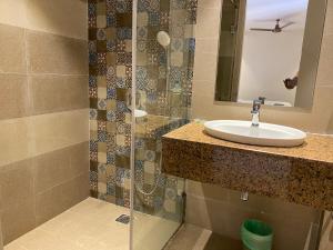 ein Bad mit einem Waschbecken und einer Dusche in der Unterkunft Hotel Ami Grace in Port Blair