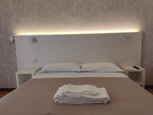 Albergo Conca d'Oro في ريميني: سرير ابيض عليه منشفة بيضاء