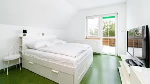 a white bedroom with a white bed and a green floor at Apartamenty Sun & Snow Villa Sportowa in Mysłakowice