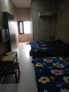 Habitación con 2 camas y mesa. en HOTEL JOGI GUEST HOUSE, en Amritsar