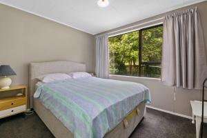 Rotoiti的住宿－Point Retreat - Lake Rotoiti Holiday Home，一间卧室设有一张床和一个大窗户