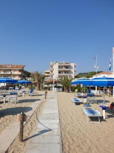 einen Strand mit Stühlen und blauen Sonnenschirmen darauf in der Unterkunft Vistamare in Silvi Marina