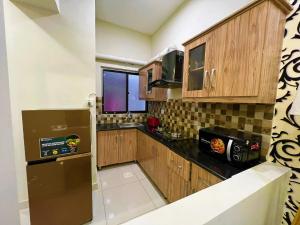 una pequeña cocina con armarios de madera y nevera. en The Realtors Inn 1 BDR Apartment DHA 2 en Islamabad