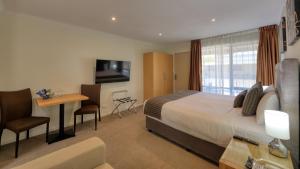 a hotel room with a bed and a table and a desk at New Crossing Place Motel in Seymour