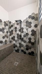 a bathroom with black and white tiles on the wall at Villa des 3 sables, CAPUCIN in Étang-Salé les Bains