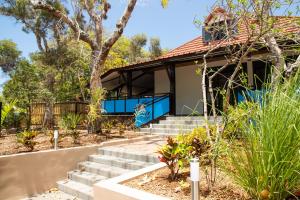 una casa con un porche delantero azul y escaleras en Villa des 3 sables, CAPUCIN en Étang-Salé les Bains