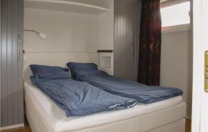 Una cama con sábanas azules y una ventana en una habitación en Two-Bedroom Apartment In Strandvik, en Dalland