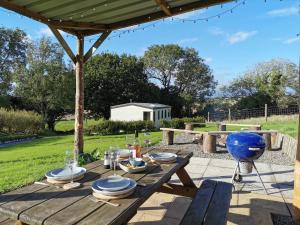 a wooden picnic table with plates of food on it at Secluded Farmland Retreat - Valley View in Totnes