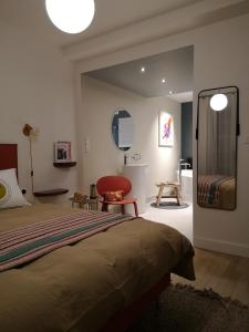 a bedroom with a bed and a mirror and a chair at Maison et Florescence in Nuits-Saint-Georges