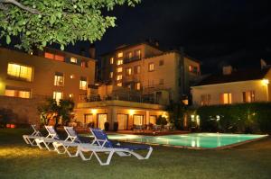 a group of chairs sitting next to a swimming pool at night at Hotel Solé in La Pobla de Segur