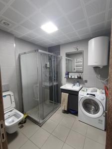 een badkamer met een douche, een wastafel en een wasmachine bij 18th Floor Secure Luxury Condo With Pool & Fitness Included In Price in Skopje