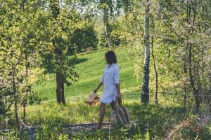 a woman walking through the woods with a suitcase at Łubinowe Wzgórze - Wioska Zdrowia in Nałęczów