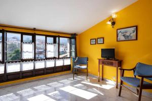 a living room with yellow walls and a tv and chairs at Casa rural El Cotero Lines in Porrúa