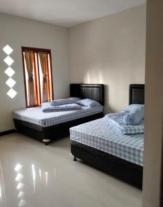 Bromo Seruni Astungkara Homestay في بروبولينغو: سريرين في غرفة مع سريرين sidx sidx