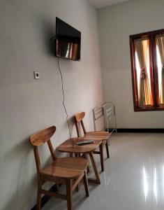 Bromo Seruni Astungkara Homestay في بروبولينغو: غرفة بها كرسيين وطاولة وتلفزيون