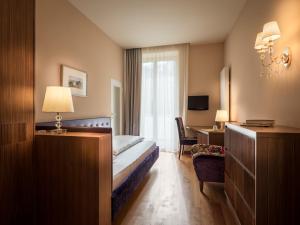 メラーノにあるHotel Palmaのベッドとデスクが備わるホテルルームです。