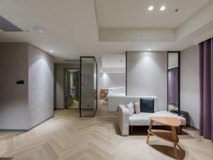 a living room with a white couch and a chair at Dahu Park Hotel in Taipei
