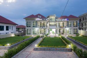 a large white house with a garden in front of it at The city Block Apartment in Bujumbura