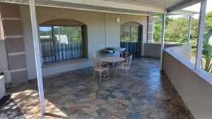 une terrasse couverte avec une table et des chaises. dans l'établissement 8 On Eagle Self Catering Apartment, à Umtentweni