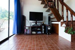 Charming 6-Bed House in Puerto Galera في بويرتو غاليرا: غرفة معيشة مع تلفزيون وأرضية من البلاط