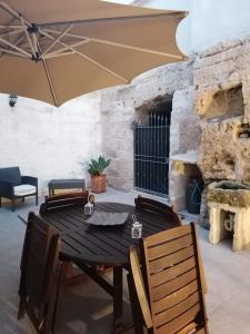 a wooden table with chairs and an umbrella at ANTICO CORTILE Favignana in Favignana
