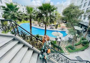a woman standing on a staircase with an umbrella next to a pool at Silk Path Grand Hue Hotel in Hue