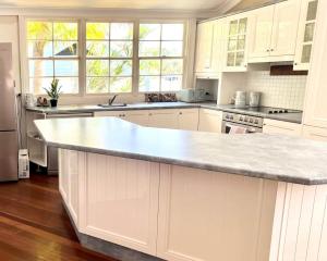 a kitchen with white cabinets and a marble counter top at Blue Pearl - Old Bar Holiday Rentals in Old Bar
