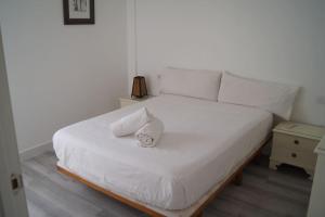Una cama blanca con dos almohadas encima. en ROCH - Stylish Apartment near Metro, en Sevilla