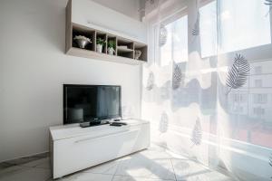 a white living room with a tv and a window at Il Parco 7 by Quokka 360 - in the business centre of Lugano in Lugano