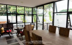 a dining room with a table and chairs and windows at de'Govin Hotel in Tjakranegara