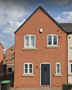 a brick house with a black door and three windows at Sutton House in Sutton in Ashfield