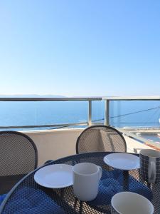 a table on a balcony with a view of the ocean at Apartments Majic Zivogosce in Živogošće