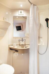 La salle de bains est pourvue d'un lavabo, de toilettes et d'un miroir. dans l'établissement Premiere Classe Maubeuge, à Feignies