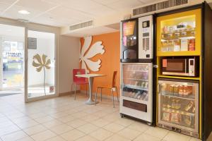 a restaurant with a refrigerator and a table in it at Premiere Classe Maubeuge in Feignies