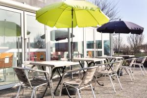 Premiere Classe Maubeuge في Feignies: صف من الطاولات والكراسي مع المظلات