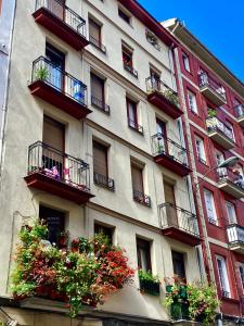 un edificio alto con balcones y flores. en Apartamento Puerta del Camino 1, en Bilbao