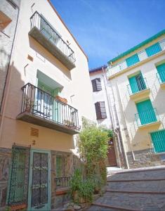 un edificio con 2 balcones y un árbol en una calle en 2EGA37 Studio en centre-ville, en Collioure